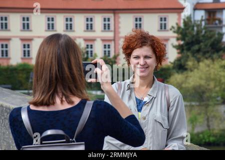 Turisti felici a Praga, Repubblica Ceca, che scattano selfie e foto di un altro passeggero in una giornata di sole durante le loro vacanze. Foto Stock