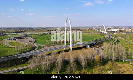 Veduta aerea zenithal di una rotatoria con un arco del ponte sospeso di Santiago Calatrava a Reggio Emilia. Reggio Emilia, Italia Foto Stock