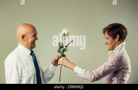 L'uomo calvo dà una rosa alla sua anziana moglie che la riceve con gioia ed emozione. Si amano, si stimano e si rispettano a vicenda come hanno sempre fatto dal Foto Stock