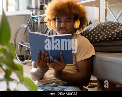 Giovane afroamericano che legge un libro in un appartamento moderno Foto Stock