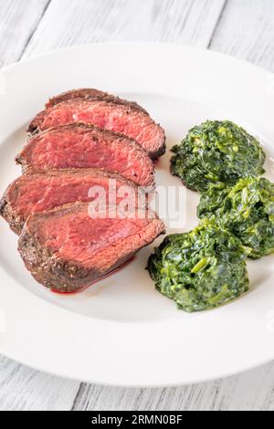 Fianchi la bistecca con gli spinaci cremosi sul piatto Foto Stock