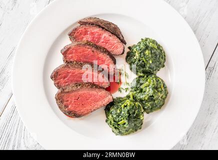 Fianchi la bistecca con gli spinaci cremosi sul piatto Foto Stock