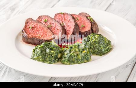 Fianchi la bistecca con gli spinaci cremosi sul piatto Foto Stock