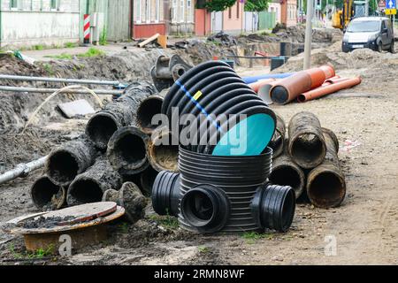 Vista sulla ricostruzione della strada, vecchi e nuovi tubi sotterranei accanto a una profonda e ampia trincea, sostituzione dei tubi Foto Stock