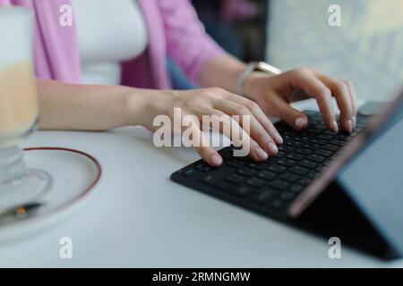 Laptop e donna mani sulla tastiera del laptop sul tavolo del caffè in primo piano Foto Stock