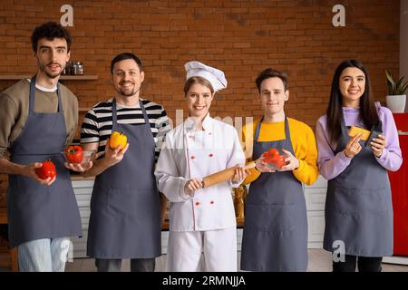 Chef donna con pizza italiana preparata e gruppo di giovani dopo la lezione di cucina in cucina Foto Stock