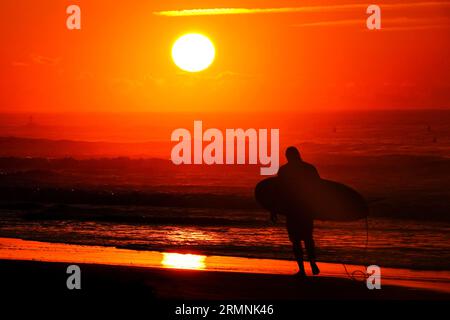 Isola di Palms, Stati Uniti. 29 agosto 2023. Un surfista, sagomato dalla drammatica alba, controlla le condizioni delle onde causate dal passaggio dell'uragano Franklin prima di uscire in acqua, il 29 agosto 2023 a Isle of Palms, South Carolina. L'uragano Franklin, una tempesta di mostri di categoria 4 si dirige alle Bermuda, mentre l'uragano Idalia dovrebbe sorvolare giovedì. Crediti: Richard Ellis/Richard Ellis/Alamy Live News Foto Stock