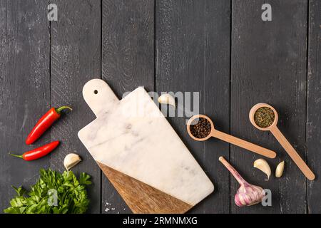 Composizione con tagliere, spezie e verdure su fondo di legno scuro Foto Stock