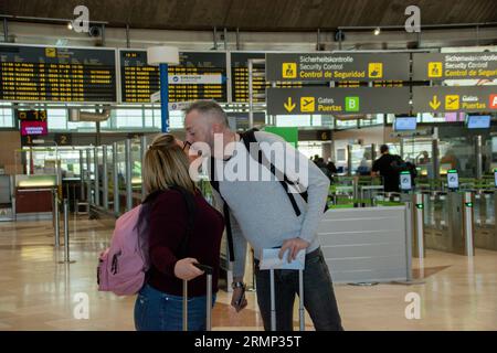 Un paio di giovani viaggiatori caucasici che si baciano all'ingresso dell'aeroporto prima di partire Foto Stock