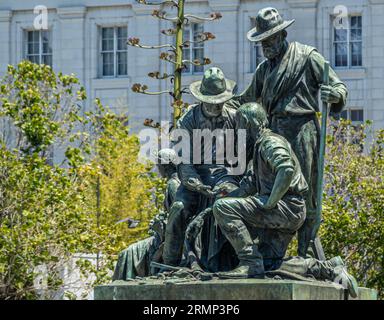 San Francisco, CA, USA - 12 luglio 2023: Monumento dei pionieri in Fulton Street, nel 49, statua del gruppo della corsa all'oro sul lato ovest. Facciata bianca della biblioteca pubblica Foto Stock