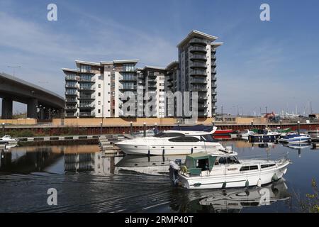 Barche sul fiume Ely nella baia di Cardiff, Galles, con moderni appartamenti lungo il fiume. Foto Stock