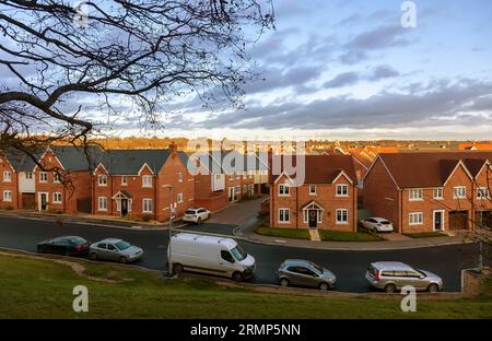 Una nuova tenuta residenziale in una mattinata molto presto di dicembre, vista l'alba che diffonde la sua luce sui tetti sotto le nuvole che si infrangono. Foto Stock