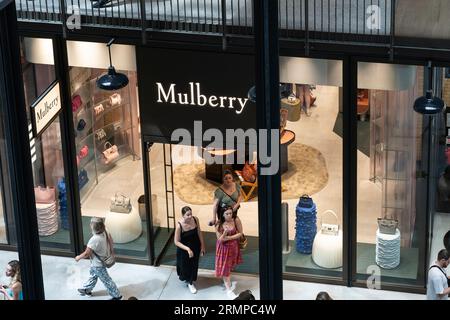 Gli amanti dello shopping possono fare shopping in un negozio outlet Mulberry nella turbine Hall A all'interno della centrale elettrica di Battersea, classificata di grado II, a Londra, Inghilterra Foto Stock