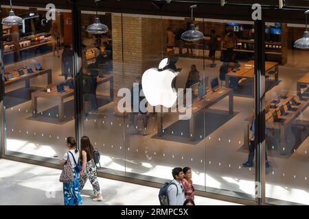 Gli acquirenti che esplorano i prodotti Apple in un Apple Store nello sviluppo rinnovato della Battersea Power Station con il logo Apple in evidenza. Londra, Regno Unito Foto Stock