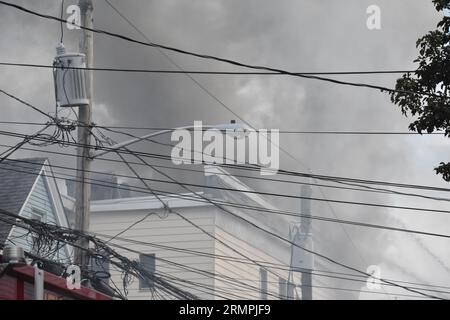 Newark, Stati Uniti. 29 agosto 2023. Le fiamme sparano dal tetto della casa di Newark. I vigili del fuoco hanno combattuto le fiamme scoppiate in una casa multifamiliare da un incendio a Newark. L'incendio a due allarmi è scoppiato in un condominio di tre piani situato al 634 della 15th Avenue intorno alle 17:00, martedì pomeriggio. Non sono state riportate ferite. Credito: SOPA Images Limited/Alamy Live News Foto Stock