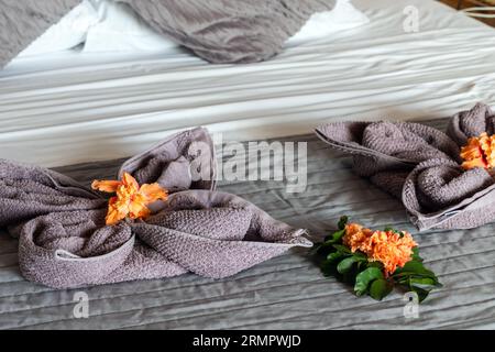 L'arredamento della camera da letto, gli asciugamani e i fiori sono sul letto della camera d'albergo Foto Stock