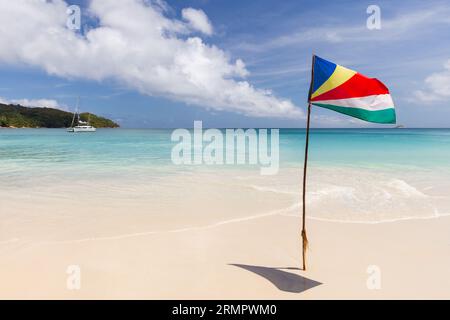 La bandiera delle Seychelles montata sulla spiaggia sventolava in una giornata di sole Foto Stock