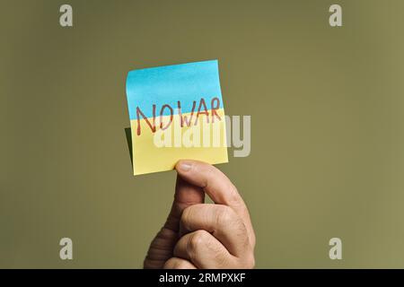 Mano dell'uomo con un adesivo, sotto forma di bandiera Ucraina con l'iscrizione "no War" Foto Stock