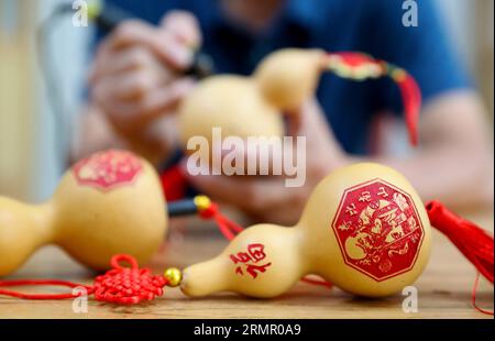 Un artigiano espone le sue opere d'arte della zucca nella città di Laixi, nella provincia dello Shandong della Cina orientale, il 27 agosto 2023. Foto Stock