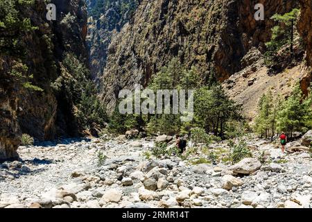 Escursionisti in una stretta gola con enormi e torreggianti scogliere su entrambi i lati (Samaria Gorge, Grecia) Foto Stock