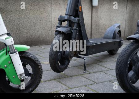 Scooter elettrici Dockless da noleggiare tramite app, parcheggiati in una strada cittadina. Sistema di condivisione scooter, noleggio di un veicolo moderno con telefono cellulare. Foto Stock