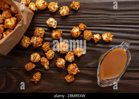 Popcorn caramellato in sacchetto di carta su tavolo da cucina in legno piatto Foto Stock
