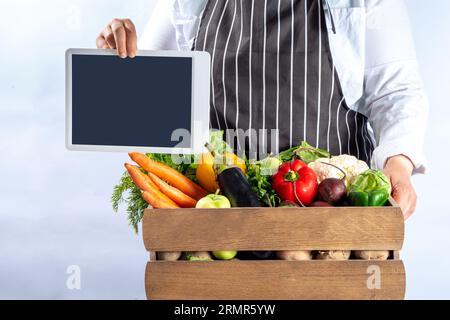 Concetto di shopping del mercato biologico agricolo, scatola di legno con estate, verdure crude e frutta autunnali, mani contadine su sfondo bianco Foto Stock