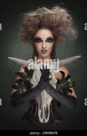Misterioso ritratto di donna. Concept dark art collage di strega tiene in mano un teschio di animale morto per un rituale. Foto Stock