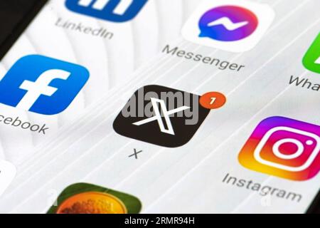 Logo iniziale di Twitter o X e app su uno smartphone. Social media online e servizio di social networking con notifica rossa e altre app Foto Stock