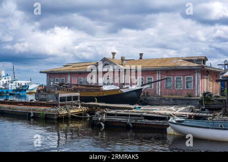 vecchi moli di legno, una nave a vela è ormeggiata accanto a una casa galleggiante del molo Foto Stock