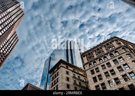 Il grattacielo Exchange Place sorge sopra gli edifici più vecchi che lo circondano, con il cielo blu e le nubi rotte che si riflettono sull'edificio Foto Stock