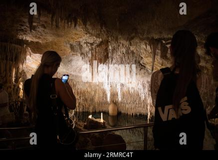 Manacor, Spagna. 28 agosto 2023. I visitatori delle grotte del Drago a Porto Cristo, uno dei luoghi più visitati di Maiorca. Con un'altezza massima di 25 metri sotto la superficie, il percorso è lungo circa 1,2 chilometri e presenta un gran numero di stalattiti e stalagmiti. Le grotte si nascondono in un grande lago sotterraneo, il lago Martel, considerato uno dei più grandi laghi sotterranei del mondo. Crediti: Clara Margais/dpa/Alamy Live News Foto Stock