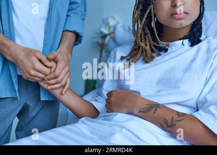 concetto di aborto spontaneo, uomo che tiene la mano di depresso moglie afroamericana, confortante, ospedale, raccolto Foto Stock