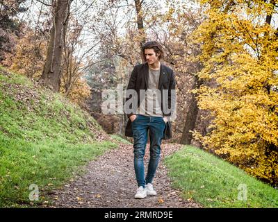 Un uomo che cammina lungo un sentiero nel bosco. Foto di un uomo che cammina attraverso un sereno sentiero nella foresta Foto Stock