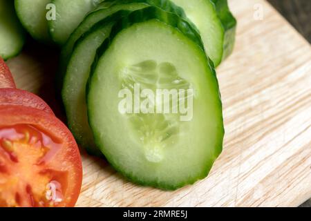 Cetriolo lungo verde a fette durante la preparazione dell'insalata, preparazione dell'insalata con verdure tagliate a pezzetti di cetrioli verdi Foto Stock