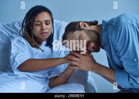 concetto di aborto spontaneo, uomo triste in lutto e tenendo per mano la moglie afroamericana, reparto ospedaliero Foto Stock