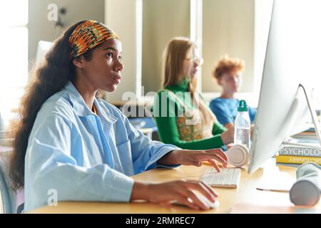 Gruppo di studenti seduti alla scrivania e che imparano con i computer in classe Foto Stock