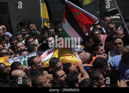 (140726) -- HEBRON, 26 luglio 2014 (Xinhua) -- i luttuosi trasportano il corpo del 26enne Eid palestinese Rabah Fdilat, che i medici hanno detto sia stato ucciso durante gli scontri con le truppe israeliane venerdì, durante i suoi funerali nel campo profughi di Arroub, a nord della città di Hebron, il 26 luglio 2014. I medici hanno detto che otto palestinesi sono stati uccisi negli scontri nei pressi delle città di Nablus ed Hebron in Cisgiordania venerdì, dopo le proteste contro l'operazione militare israeliana nella Striscia di Gaza. (Xinhua/Mamoun Wazwaz) MIDEAST-HEBRON-FUNERALE PUBLICATIONxNOTxINxCHN Hebron luglio 26 2014 XINHUA Morne Carry the Body of 26 Year Old Foto Stock