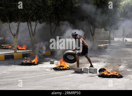 (140730) -- SANAA, 30 luglio 2014 -- Uno yemenita brucia pneumatici per protestare contro la decisione del governo di aumentare drasticamente il prezzo del carburante a Sanaa, Yemen, il 30 luglio 2014. Il governo yemenita aumentò il prezzo della benzina da 125 riyal yemeniti (0,58 dollari USA) a 200 riyal per litro e sbarcò da 100 riyal a 195 riyal mercoledì, cosa che ha scatenato proteste di massa nella capitale Sanaa. I manifestanti arrabbiati bruciarono pneumatici e tagliarono molte strade a Sanaa. Il governo ha schierato più soldati per mantenere la sicurezza nella capitale. ) (Dzl) YEMEN-SANAA-PREZZO DELLA BENZINA-PROTESTA MohammedxMohammed Foto Stock