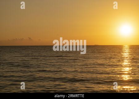 barca a vela retroilluminata attraverso i raggi del sole al tramonto in mare Foto Stock