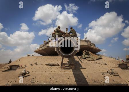 (140805) -- FRONTIERA DI GAZA, 4 agosto 2014 -- soldati israeliani siedono in cima a un carro armato Merkava nel sud di Israele al confine con la Striscia di Gaza dopo essere tornati dall'enclave palestinese il 4 agosto 2014. Israele ha accettato una proposta egiziana per un cessate il fuoco di 72 ore con il movimento palestinese di Hamas a partire dalle 8:00 ora locale (0500 GMT) di martedì, i media israeliani hanno riferito lunedì. Durante le 72 ore, una delegazione israeliana dovrebbe arrivare al Cairo, capitale dell'Egitto, per negoziare con i palestinesi, ha riportato il sito di notizie di Walla. ISRAELE-STRISCIA DI GAZA-72 ORE CESSATE IL FUOCO-ACCORDO JINI PUB Foto Stock