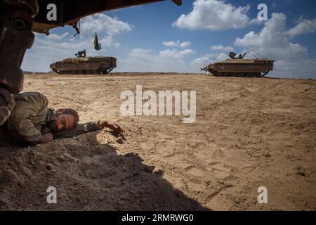 (140805) -- FRONTIERA DI GAZA, 4 agosto 2014 -- un soldato israeliano dorme sotto un veicolo militare nel sud di Israele al confine con la Striscia di Gaza dopo essere tornato dall'enclave palestinese il 4 agosto 2014. Israele ha accettato una proposta egiziana per un cessate il fuoco di 72 ore con il movimento palestinese di Hamas a partire dalle 8:00 ora locale (0500 GMT) di martedì, i media israeliani hanno riferito lunedì. Durante le 72 ore, una delegazione israeliana dovrebbe arrivare al Cairo, capitale dell'Egitto, per negoziare con i palestinesi, ha riportato il sito di notizie di Walla. ISRAELE-STRISCIA DI GAZA-72 ORE CESSATE IL FUOCO-ACCORDO J Foto Stock