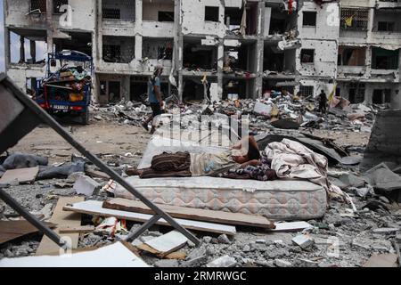 (140804) -- STRISCIA DI GAZA, 4 agosto 2014 -- Un ragazzo palestinese riposa su un materasso mentre raccoglie oggetti personali dalla sua casa distrutta nella città settentrionale di Beit Lahiya, nella Striscia di Gaza, il 4 agosto 2014. Dall'inizio dell'offensiva israeliana sulla Striscia di Gaza, 1.868 palestinesi sono stati uccisi e più di 9470 feriti, ha detto Ashraf al-Qedra, portavoce del ministero della salute a Gaza. ) MIDEAST-GAZA-ISRAELE-ATTACCO AEREO WissamxNassar PUBLICATIONxNOTxINxCHN Striscia di Gaza 4 agosto 2014 un ragazzo PALESTINESE poggia SU un materasso mentre raccoglie i suoi membri dalla sua casa distrutta nella città settentrionale della Striscia di Gaza Foto Stock