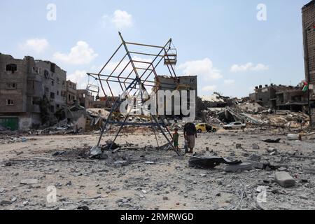 (140804) -- STRISCIA DI GAZA, 4 agosto 2014 -- Un uomo palestinese e i suoi due figli si trovano in un parco giochi danneggiato nella città settentrionale di Beit Hanoun, nella Striscia di Gaza, il 4 agosto 2014. Dall'inizio dell'offensiva israeliana sulla Striscia di Gaza, 1.868 palestinesi sono stati uccisi e più di 9470 feriti, ha detto Ashraf al-Qedra, portavoce del ministero della salute a Gaza. ) MIDEAST-GAZA-ISRAELE-CESSATE IL FUOCO WissamxNassar PUBLICATIONxNOTxINxCHN Striscia di Gaza 4 agosto 2014 un uomo PALESTINESE e i suoi due figli si trovano in un parco giochi danneggiato nella città di Beit Hanoun NELLA Striscia di Gaza settentrionale IL 4 agosto 2014 dal B Foto Stock