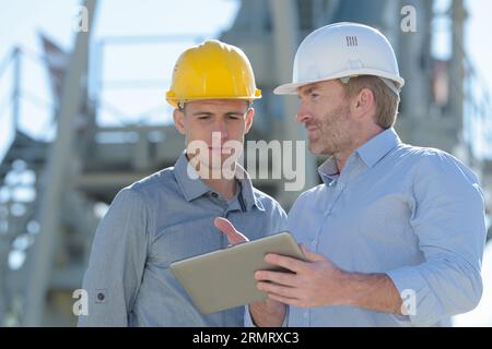 architetto e apprendista con un tablet digitale che guarda lontano Foto Stock