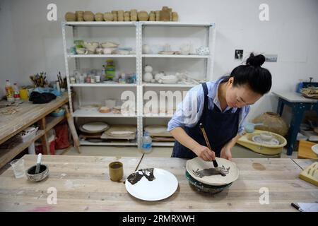 (140806) -- PECHINO, 6 agosto 2014 -- Zhang Lingyun lavora in uno studio nella sua casa a Jingdezhen, nella provincia del Jiangxi della Cina orientale, 18 luglio 2014. Zhang Lingyun ha 40 anni. Sono passati 20 anni da quando l'artista ceramico è venuto a Jingdezhen, capitale della porcellana cinese. La storia di Zhang con la ceramica ebbe un inizio casuale e romantico: Sapeva quasi nulla di ceramica prima di imbattersi nel nome Jingdezhen Ceramic Institute (JCI) quando si iscriveva al college. La ceramica sembrava interessante, quindi ho presentato la domanda per la JCI. Il capriccio d'impulso aveva fatto una grande differenza nella vita di Zhang. Il suo primo contatto wi Foto Stock