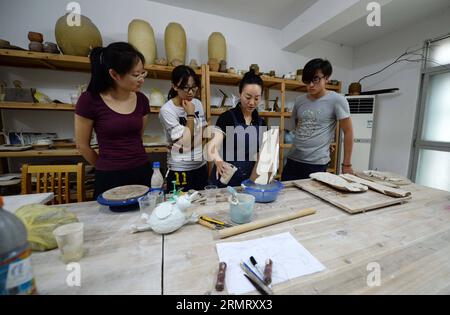 (140806) -- PECHINO, 6 agosto 2014 -- Zhang Lingyun (2nd R) tiene agli studenti una lezione in uno studio nella sua casa a Jingdezhen, nella provincia del Jiangxi della Cina orientale, 17 luglio 2014. Zhang Lingyun ha 40 anni. Sono passati 20 anni da quando l'artista ceramico è venuto a Jingdezhen, capitale della porcellana cinese. La storia di Zhang con la ceramica ebbe un inizio casuale e romantico: Sapeva quasi nulla di ceramica prima di imbattersi nel nome Jingdezhen Ceramic Institute (JCI) quando si iscriveva al college. La ceramica sembrava interessante, quindi ho presentato la domanda per la JCI. Il capriccio d'impulso aveva fatto una grande differenza nella vita di Zhang Foto Stock