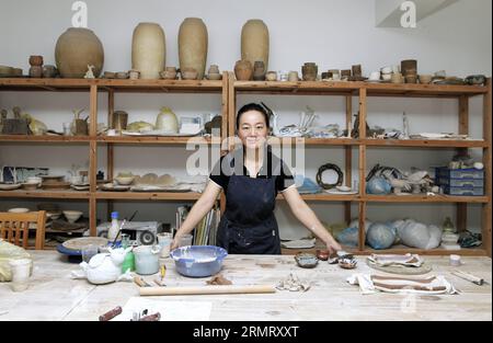 (140806) -- PECHINO, 6 agosto 2014 -- Zhang Lingyun posa per foto in uno studio nella sua casa a Jingdezhen, nella provincia dello Jiangxi della Cina orientale, 17 luglio 2014. Zhang Lingyun ha 40 anni. Sono passati 20 anni da quando l'artista ceramico è venuto a Jingdezhen, capitale della porcellana cinese. La storia di Zhang con la ceramica ebbe un inizio casuale e romantico: Sapeva quasi nulla di ceramica prima di imbattersi nel nome Jingdezhen Ceramic Institute (JCI) quando si iscriveva al college. La ceramica sembrava interessante, quindi ho presentato la domanda per la JCI. Il capriccio d'impulso aveva fatto una grande differenza nella vita di Zhang. La sua prima volta Foto Stock