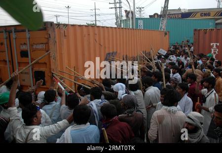 I manifestanti cercano di rimuovere un container a Lahore, Pakistan orientale, l'8 agosto 2014. La polizia pakistana ha usato proiettili di gas lacrimogeni per disperdere manifestanti anti-governativi a Lahore venerdì tardi dopo aver sequestrato un autobus della polizia, hanno detto testimoni e funzionari. Centinaia di sostenitori di un leader religioso, Tahir ul Qadri si sono scontrati con la polizia dopo aver iniziato a rimuovere i container dalle strade piazzate dalle autorità per fermare una manifestazione contro il governo il 10 agosto). PAKISTAN-LAHORE-PROTESTA Sajjad PUBLICATIONxNOTxINxCHN i manifestanti cercano di RIMUOVERE un container a Lahore nel Pakistan orientale L'8 agosto 2014 Foto Stock