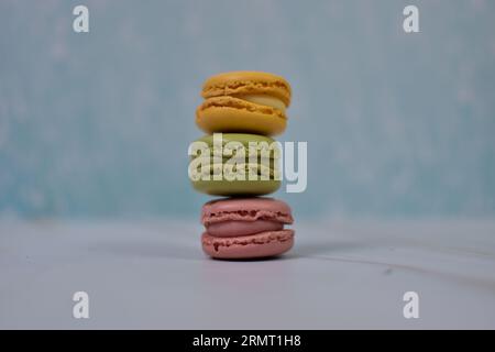 Macarons of yellow, pink and green colors stacked on sky blue background Foto Stock